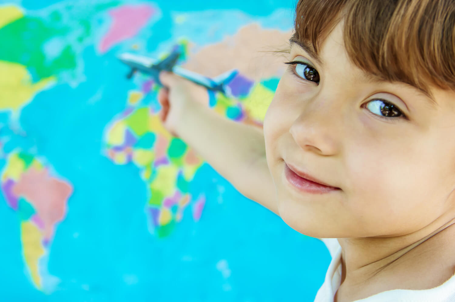 Smiling child pointing at a world map