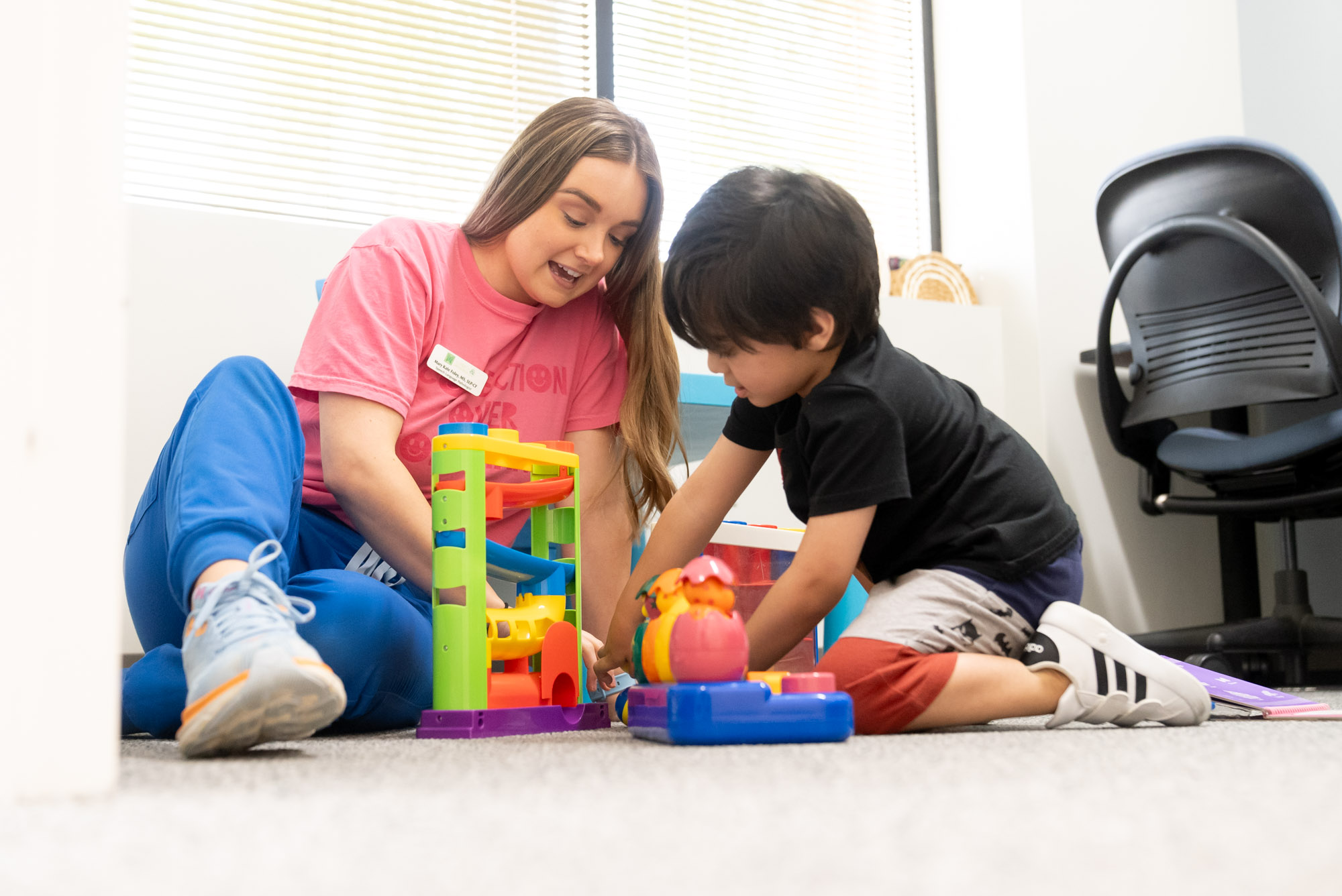 Therapist and child playing with a ball-drop toy on the floor