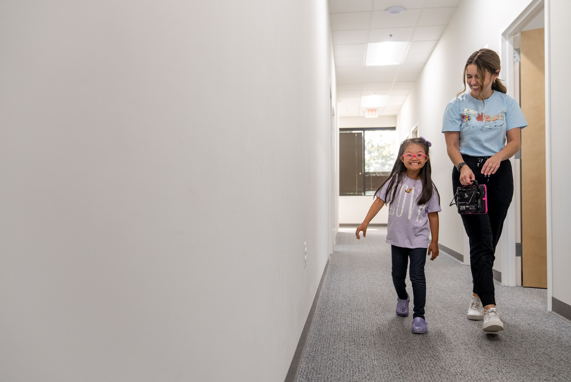 Therapist and young girl walking down a hallway together