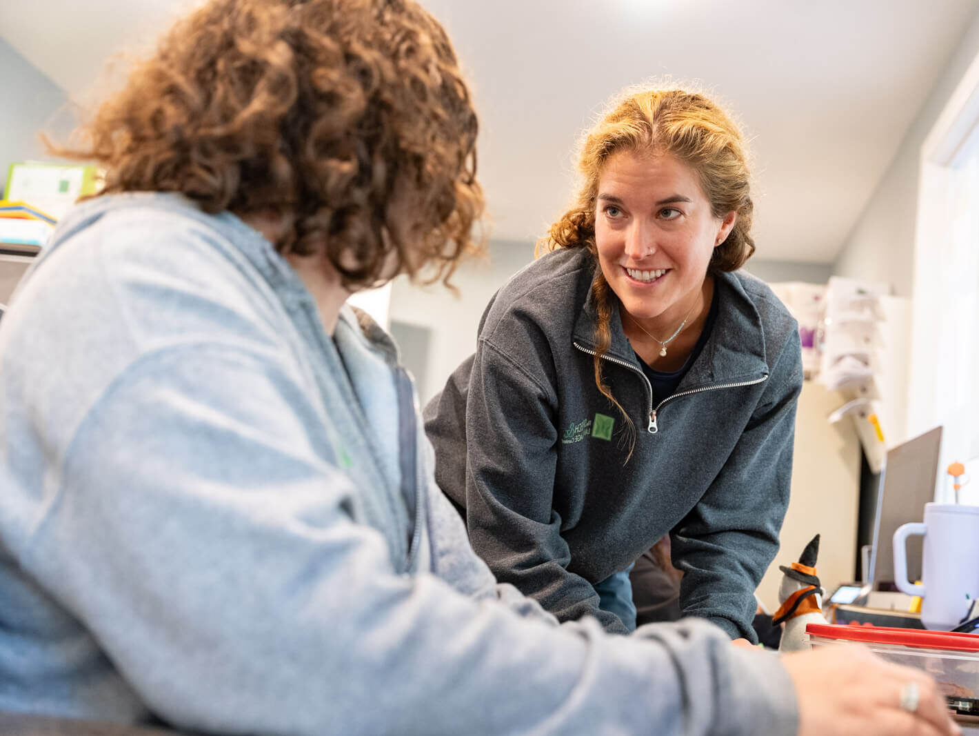 Two staff members talking and smiling at a desk
