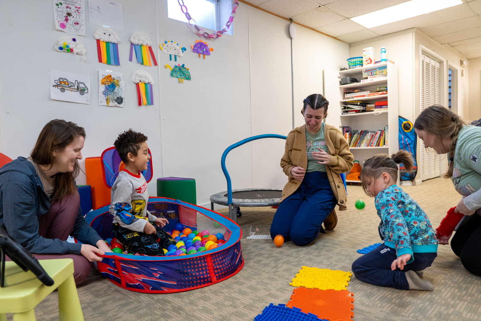 Therapists and children playing in a therapy room with a ball pit