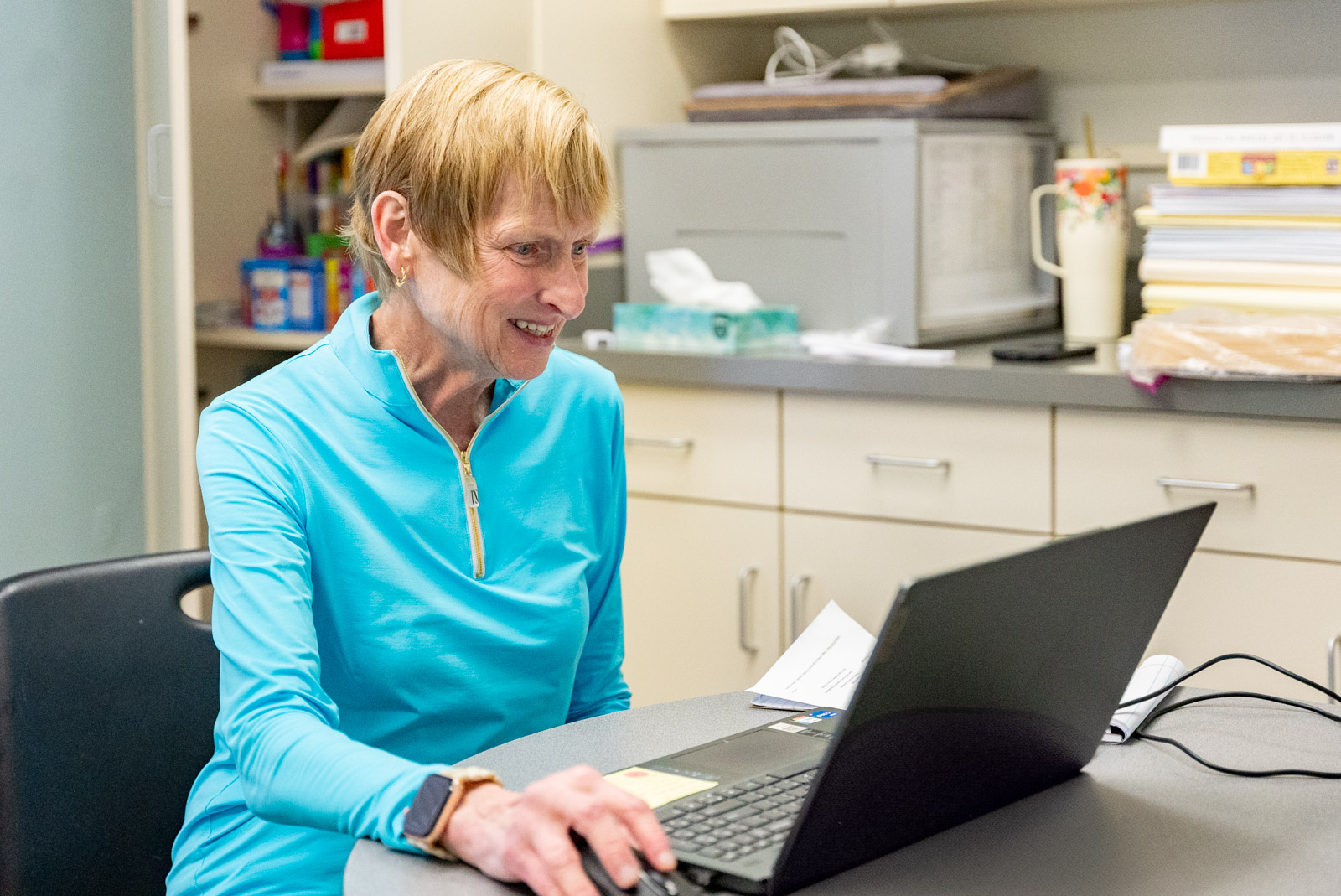Staff member smiling while working on a laptop