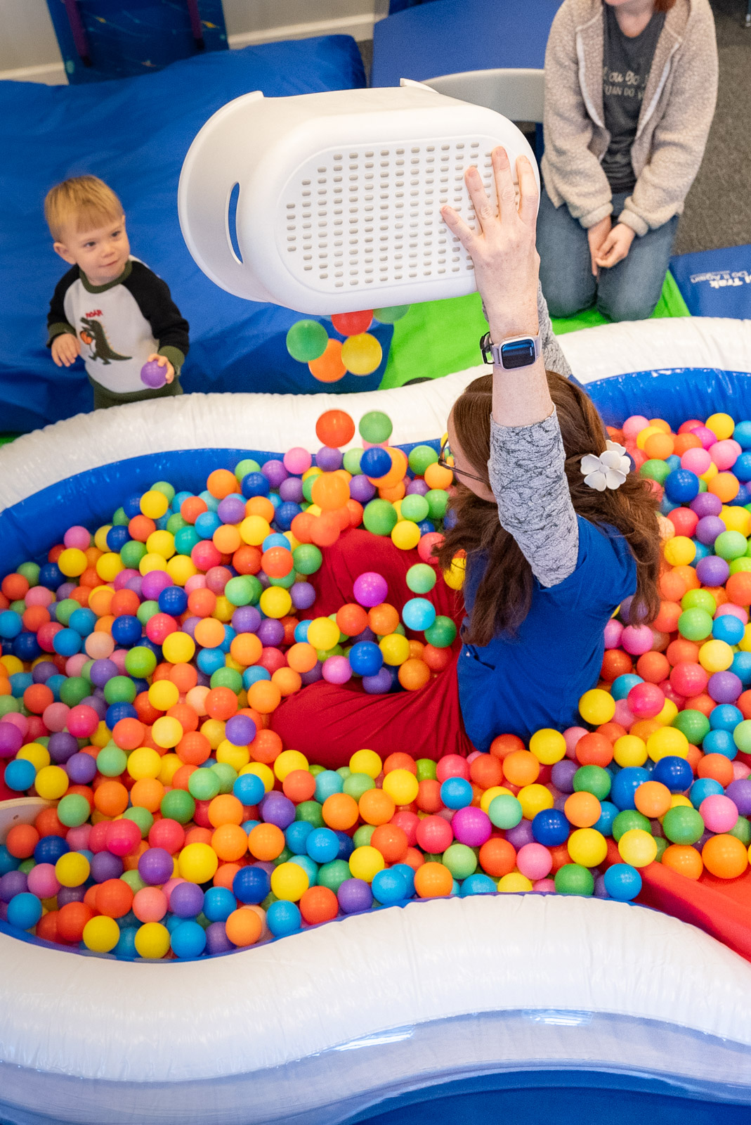 Child playing in a ball pit while a therapist looks on