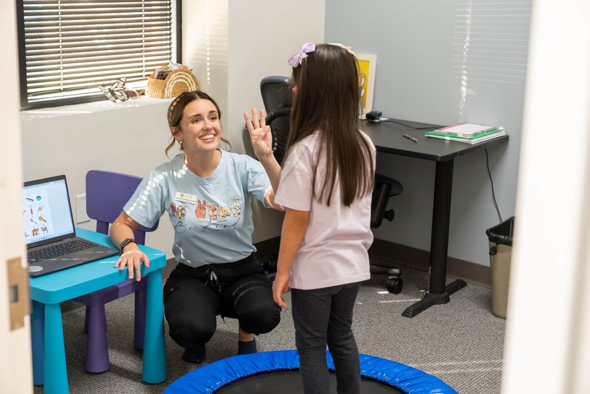 Therapist giving a high five to a young girl in a therapy room