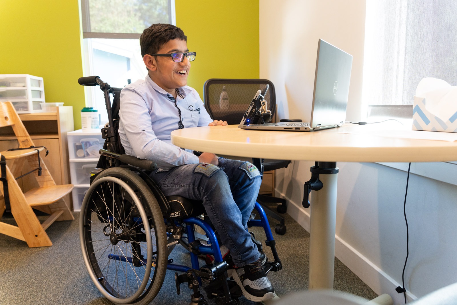 Smiling young man in a wheelchair at a table with a laptop