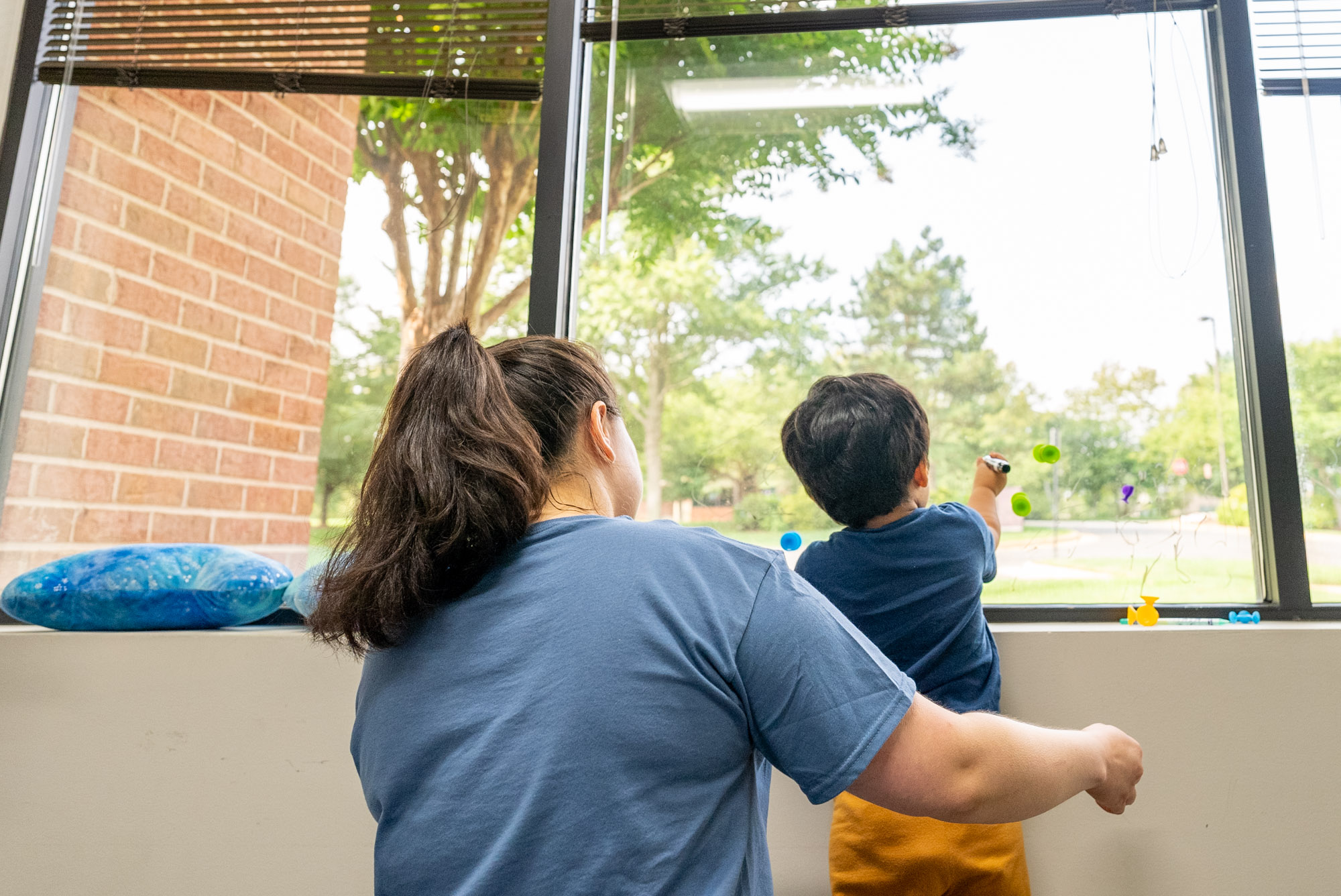 Therapist and child looking out a large window together