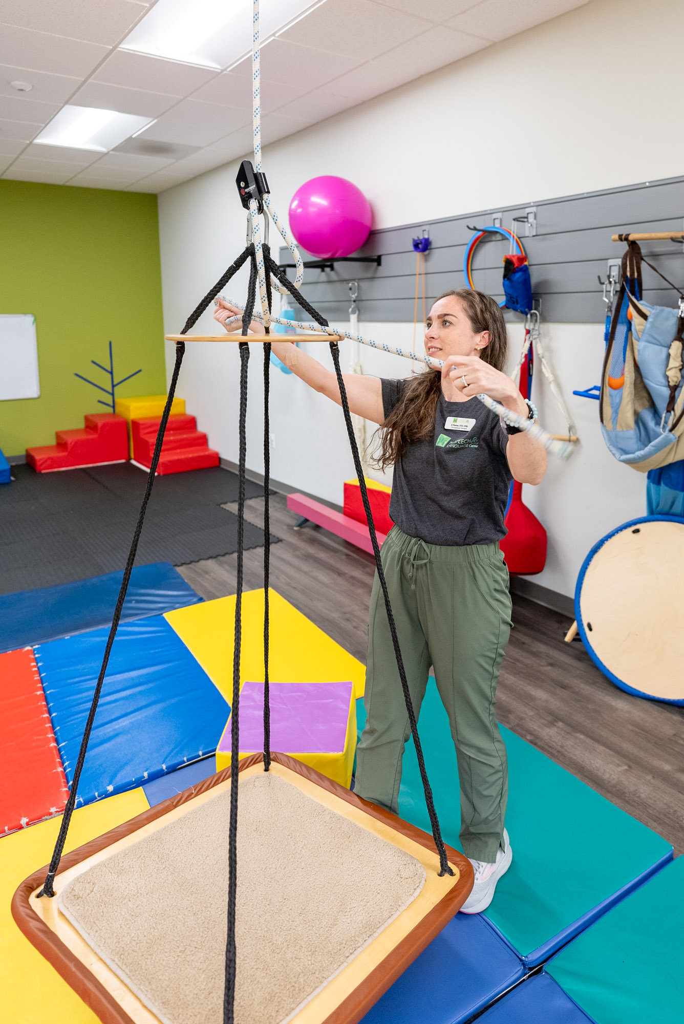 Therapist beside a platform swing in a sensory gym
