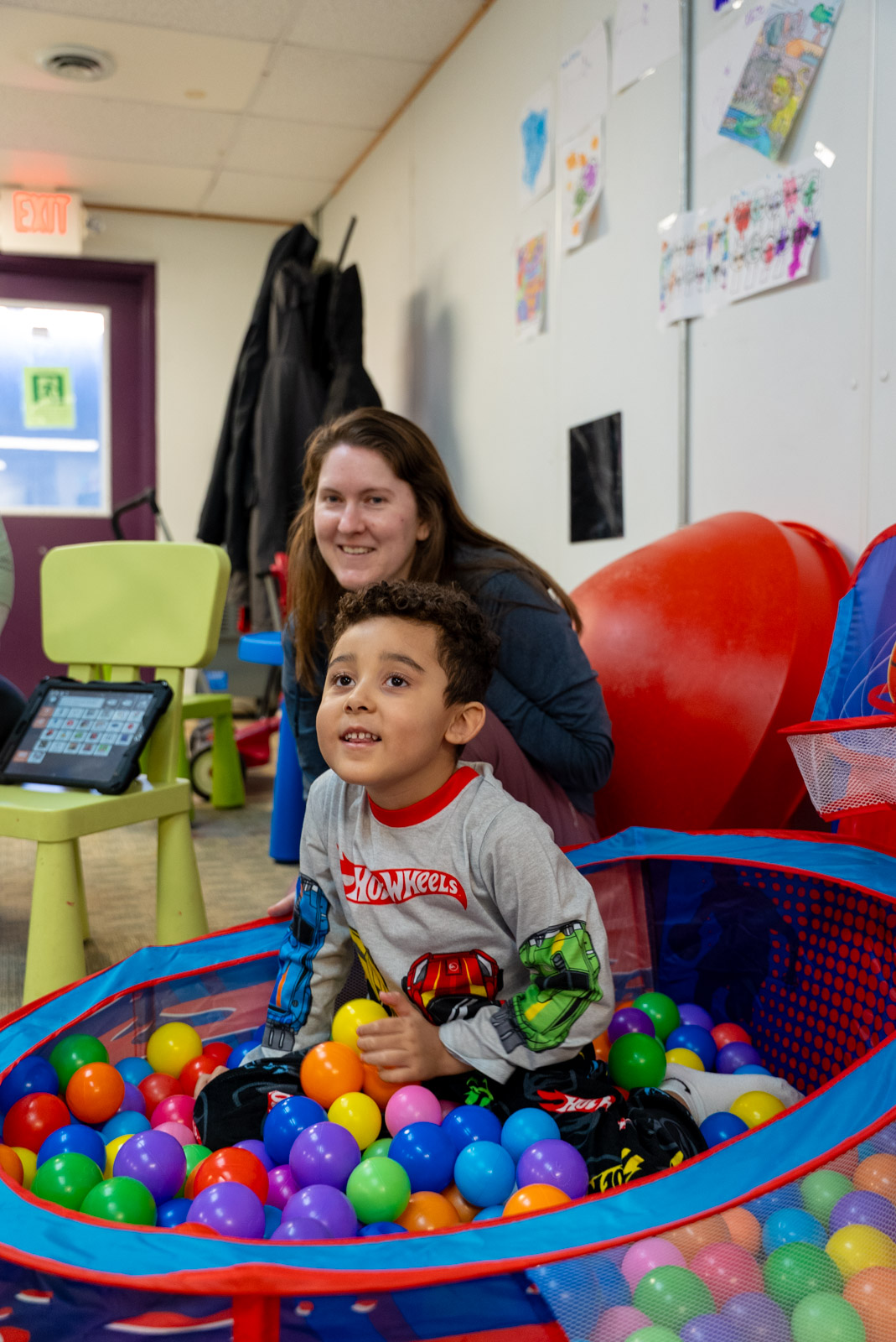 Child in a ball pit with a therapist sitting nearby
