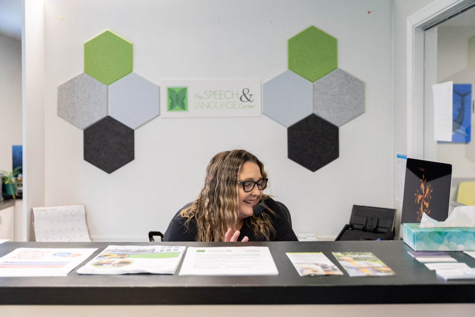 Receptionist at the front desk under The Speech & Language Center logo