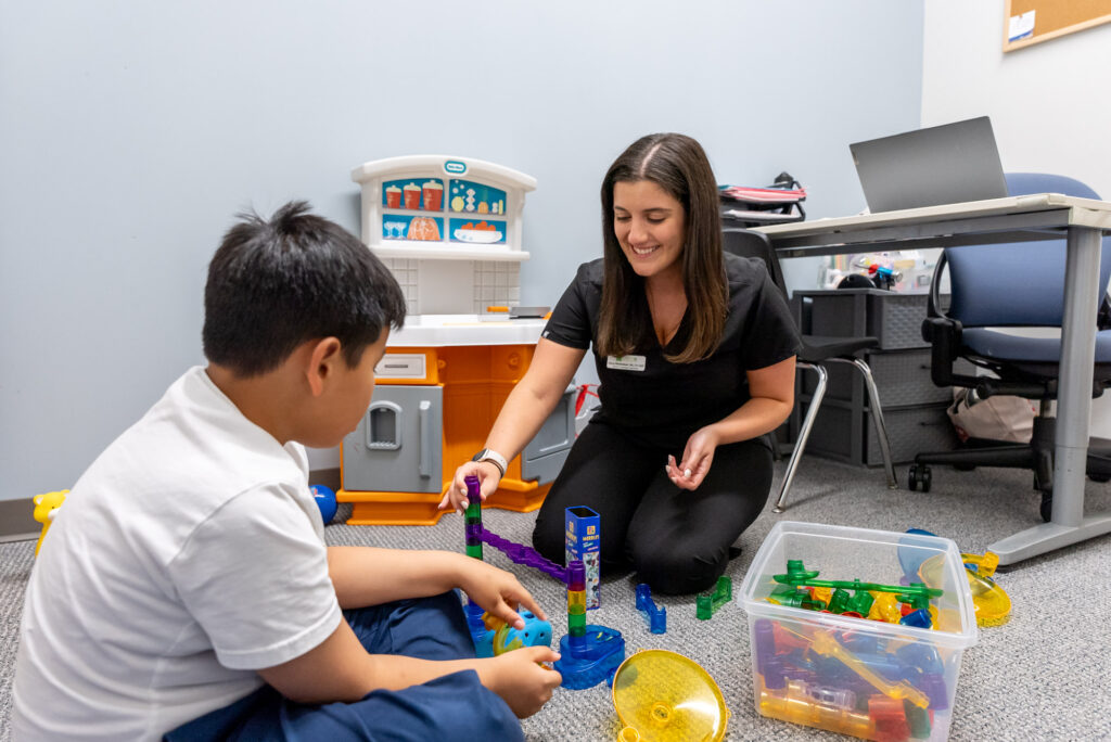 Therapist and child building with toys on the floor
