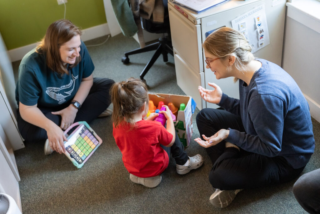 Two therapists playing with a toddler on the floor