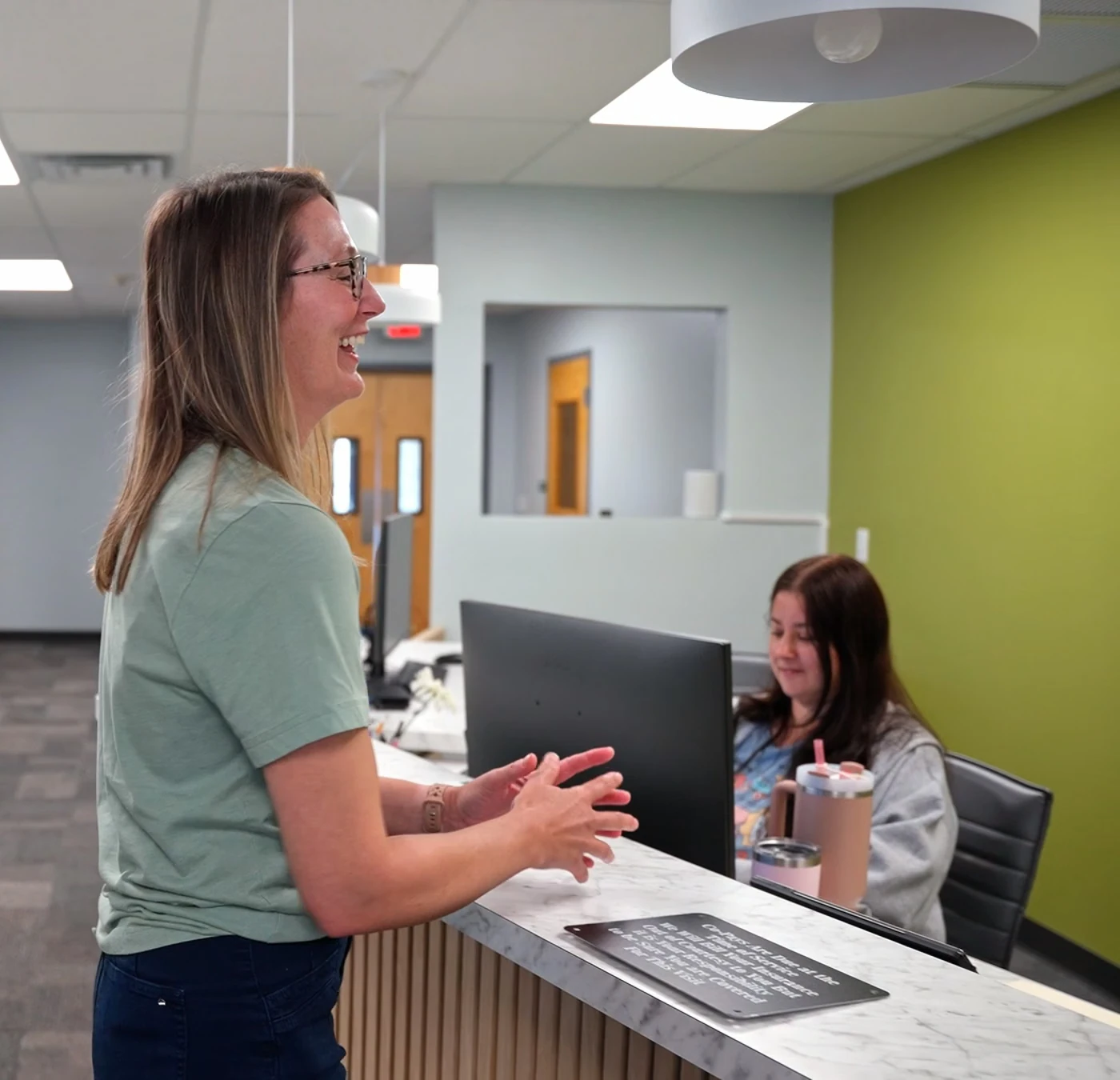 Two staff members talking at a reception desk