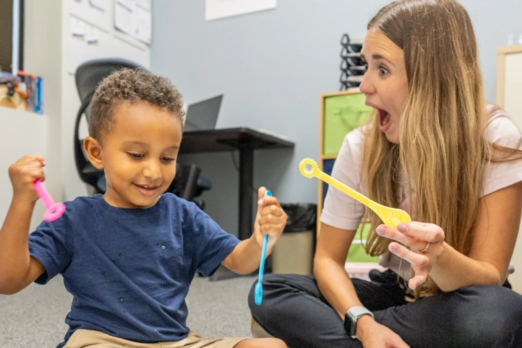 Therapist and young child playing with toys on the floor